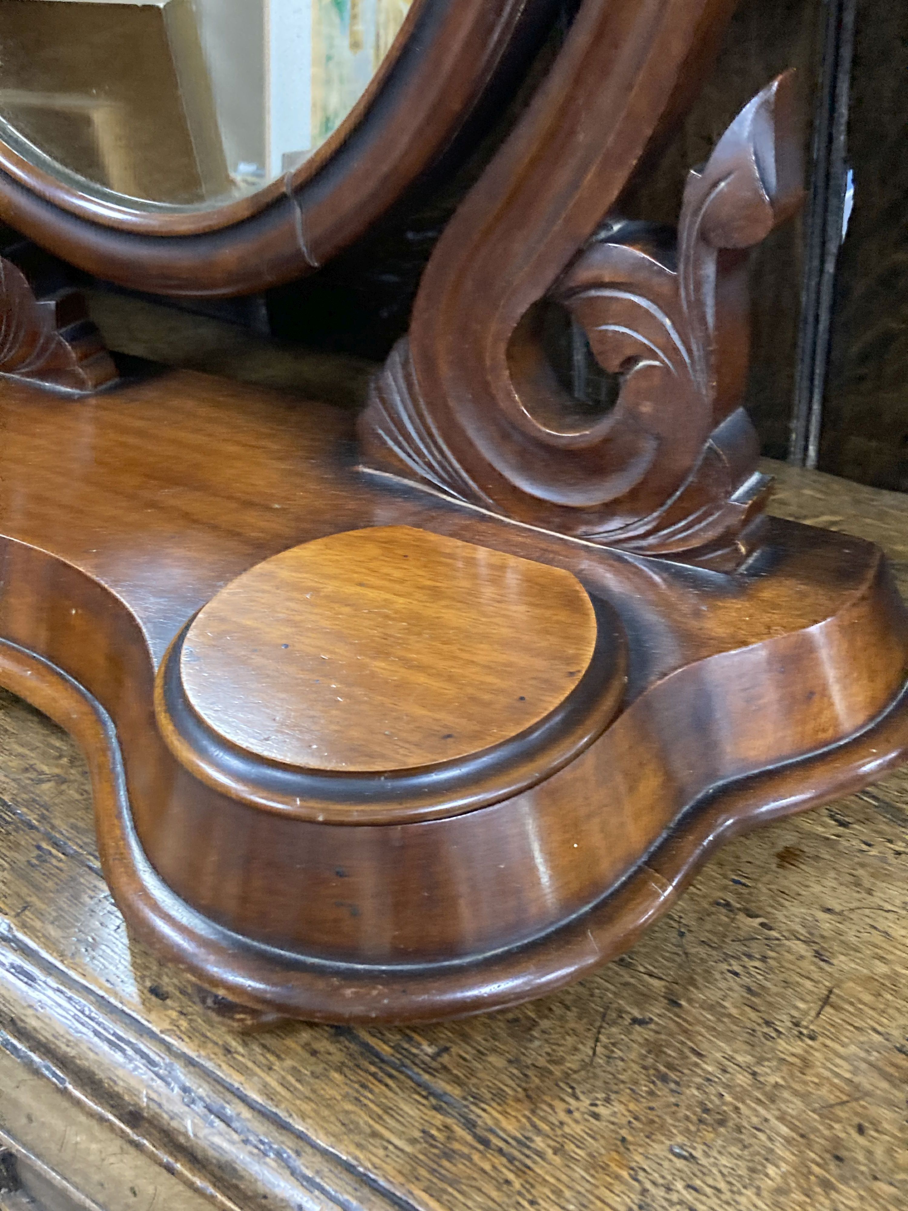 A Victorian mahogany toilet mirror of oval form above a raised platform with twin lidded compartments, width 63cm, height 71cm